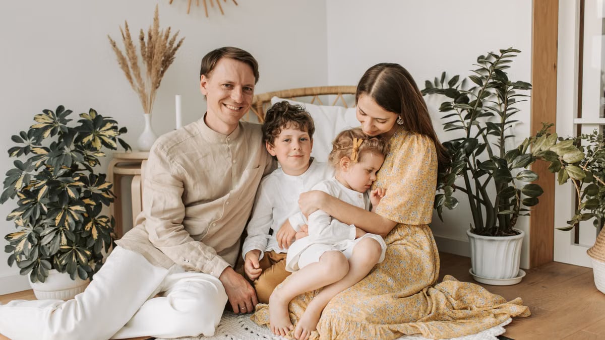 Happy family of four enjoying quality time together in a cozy, plant-filled room.
